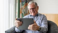 Person sitting on a chair while looking at a tablet