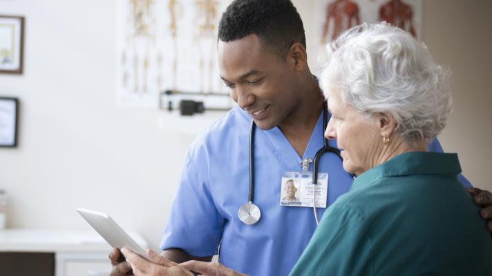 Healthcare provider talking to a patient while showing them a tablet