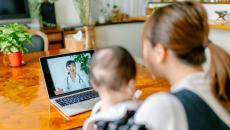 A mother and baby on a video call with a doctor.