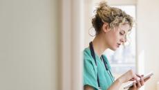 Healthcare provider standing in a doorway while looking at a tablet