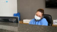 healthcare worker in mask using a phone at a desk